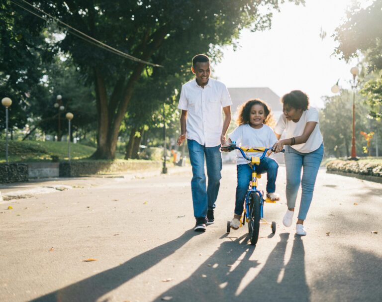 Parents helping child on bicycle