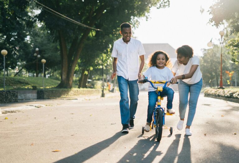 Parents helping child on bicycle
