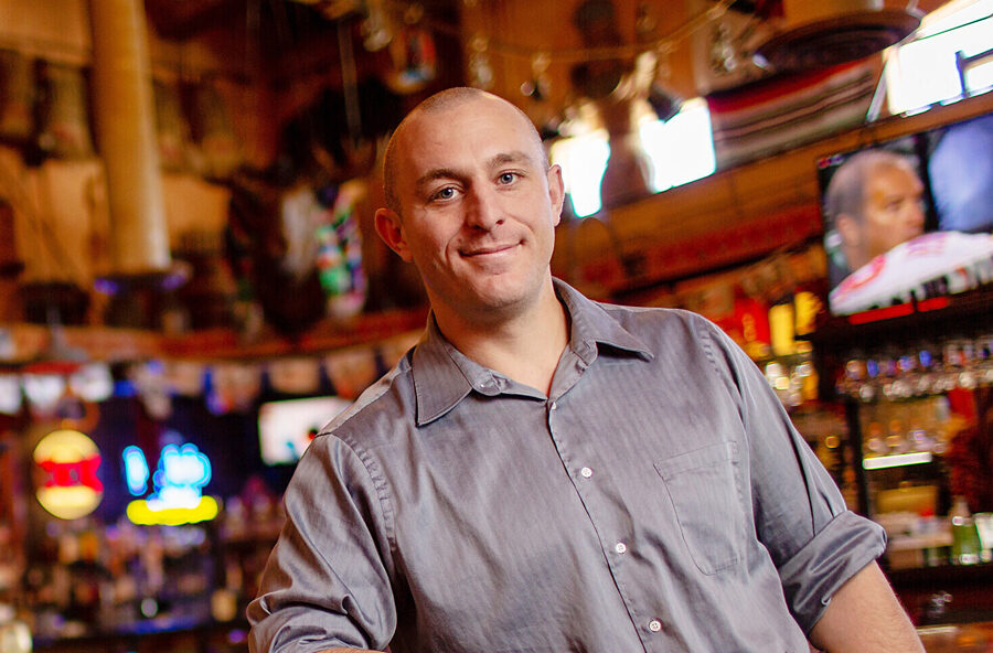 Bar owner smiling at place of business.