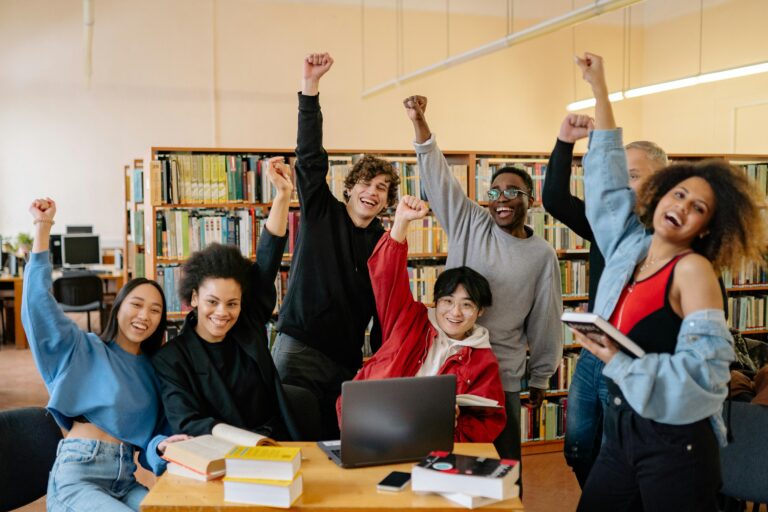 Students in a library with one arm raised celebrating
