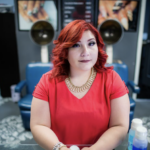 A woman sitting at a hair salon in front of two hair drying chairs.