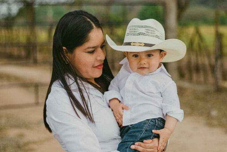 Woman holding and looking at a child dressed in Western attire.
