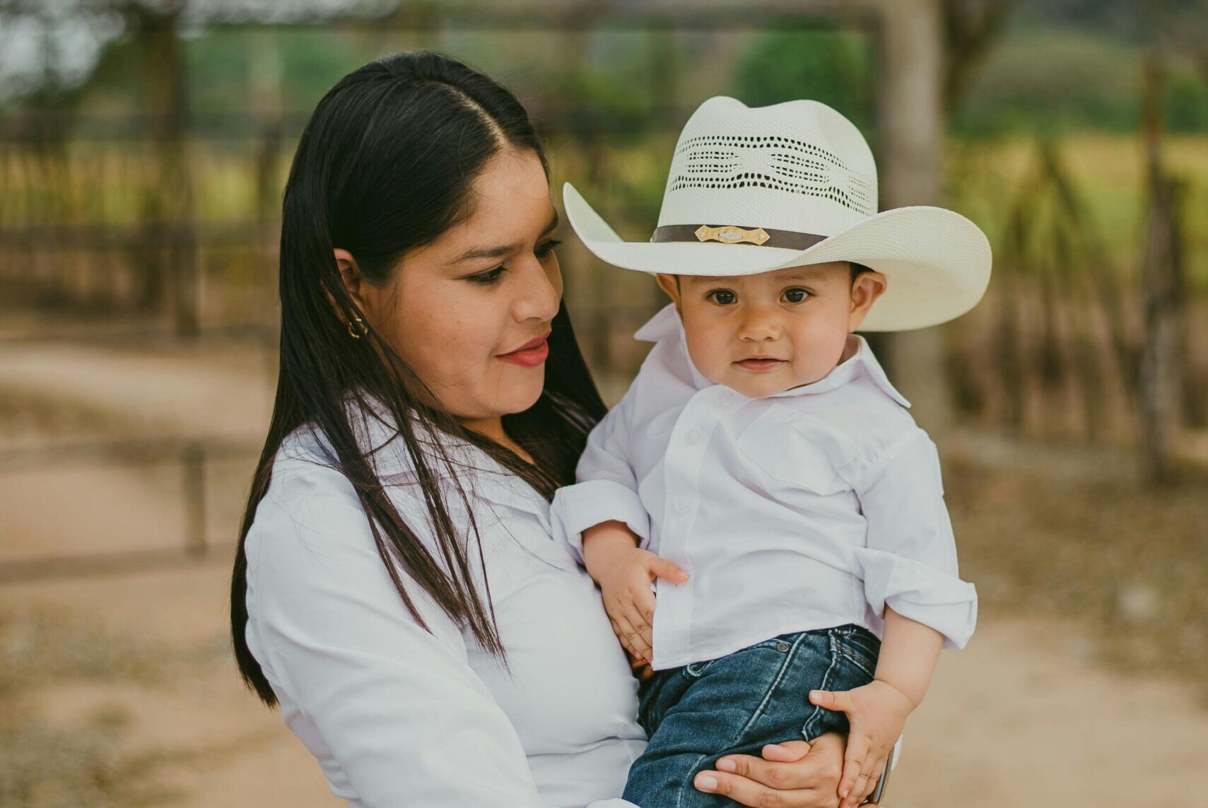 Woman holding and looking at a child dressed in Western attire.