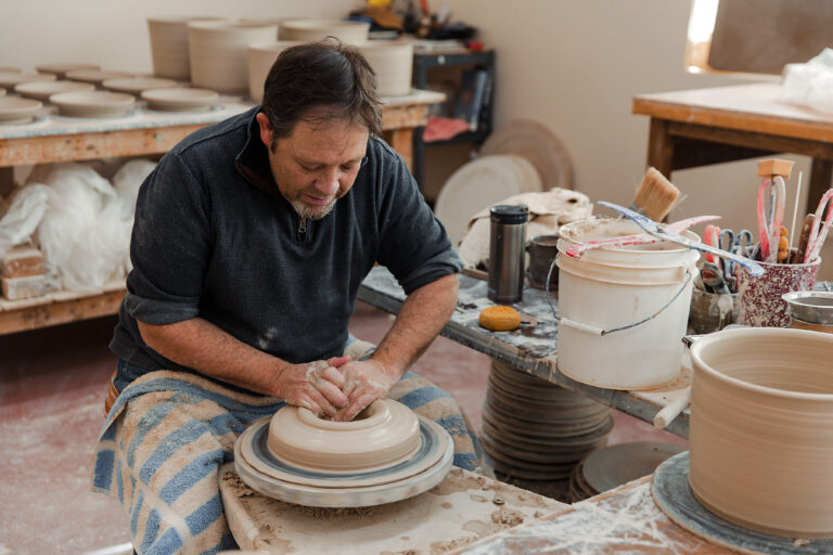 Man sitting down throwing pottery.