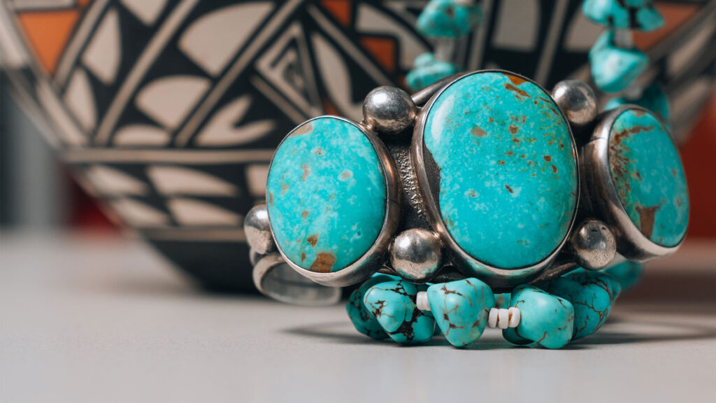 Turquoise jewelry in front of Native American pottery.