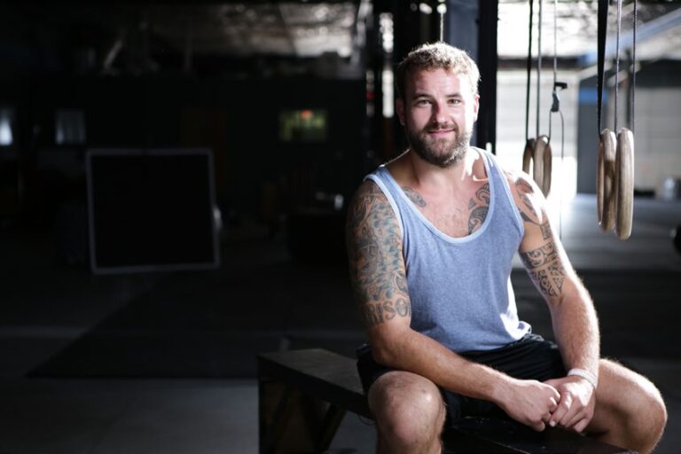 Man with tattoos sitting in a gym.