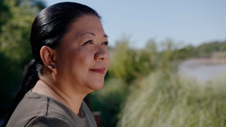 Woman standing near the Rio Grande bosque looking out into the distance.