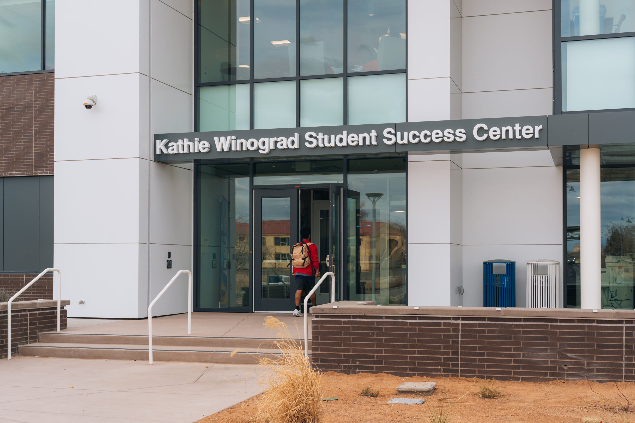 Someone with a backpack walking into the Kathie Winograd Student Success Center building