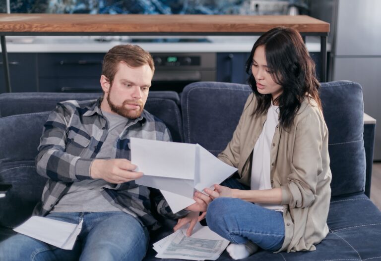 A man and a woman looking at paperwork on the couch together